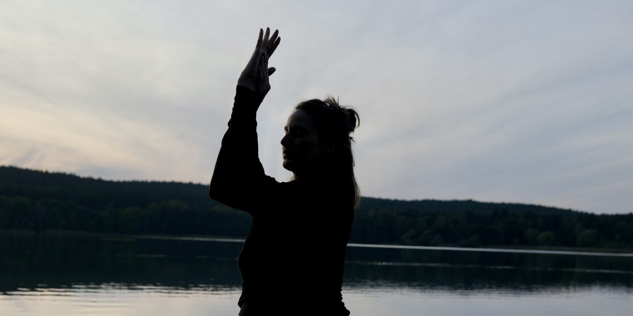 Giulia in Yoga-Pose am See bei Dämmerung